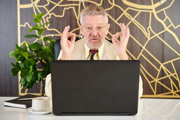Man in a suit making an OK gesture at a laptop, confident after completing a backdoor Roth IRA conversion