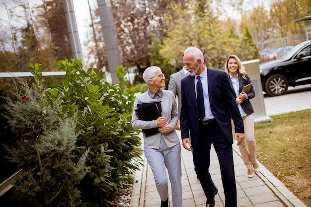 Senior professionals walking and chatting on an outdoor path near modern buildings in a walkable retirement community