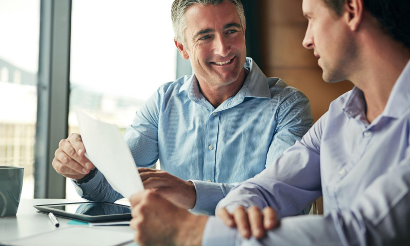 Two men reviewing a candlestick chart together, vetting a financial advisor for retirement investment guidance
