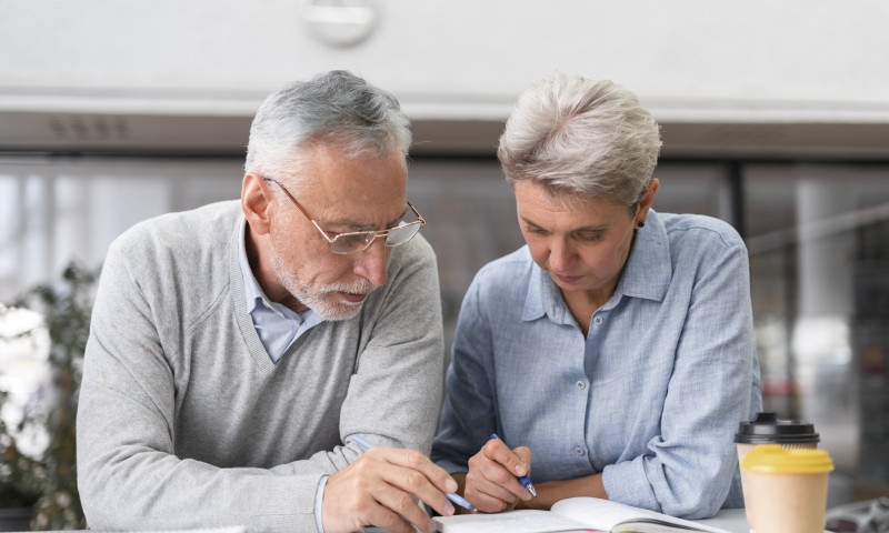 Older couple seated together writing in a notebook, carefully mapping out a Coast FIRE plan and letting compounding do the rest