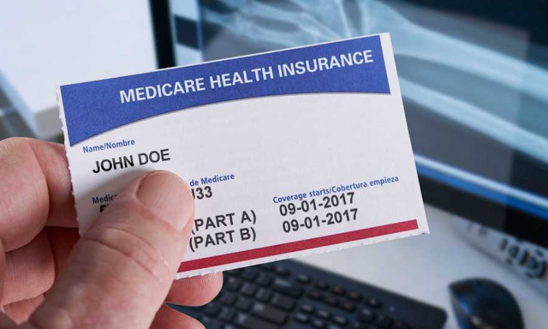 Hand holding a Medicare Health Insurance card showing Part A and Part B coverage start dates