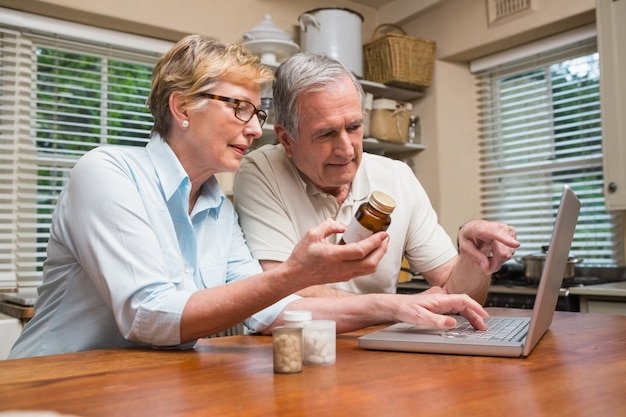 Older couple reviewing documents on a laptop, researching dividend investing strategies for retirement income