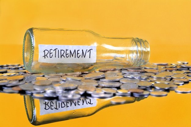 Empty Retirement bottle lying on its side amid scattered coins, representing the health insurance gap to bridge before Medicare