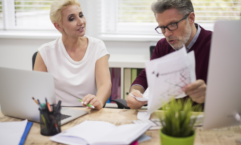 Two colleagues at an office desk reviewing printed charts, navigating what to do when an employer changes 401(k) providers