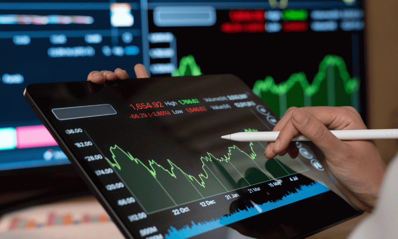 Hand using stylus on a tablet with a green stock chart, managing the urge to chase market gains near retirement