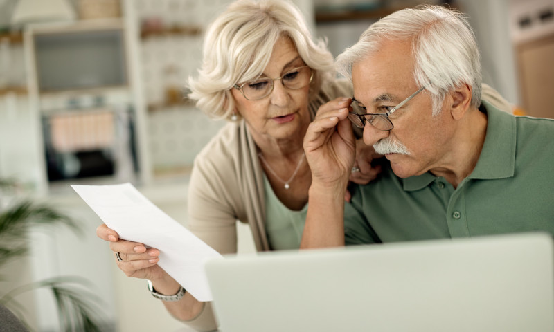 Older couple reviewing a financial document together, checking if their target-date fund aligns with retirement goals