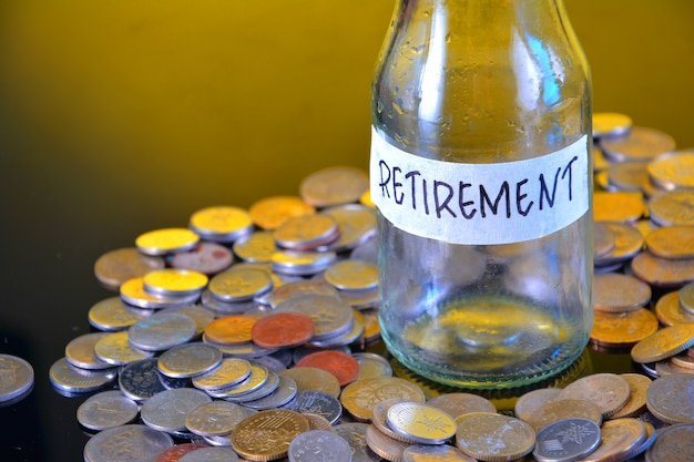Glass jar labeled Retirement surrounded by scattered coins, representing the disciplined investing needed to fund early retirement