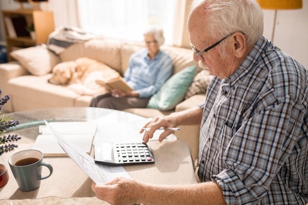 Elderly man with calculator and documents at home, researching the most tax-friendly states for retirees