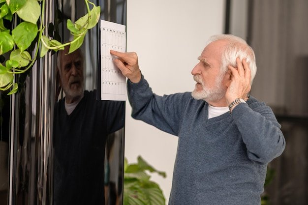 Older man pointing at a wall calendar, mapping out the multi-year timeline of a Roth conversion ladder for early retirement