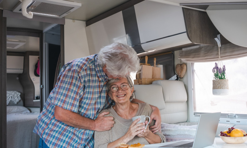 Senior couple laughing inside a modern RV camper van, considering whether RV life is right for them