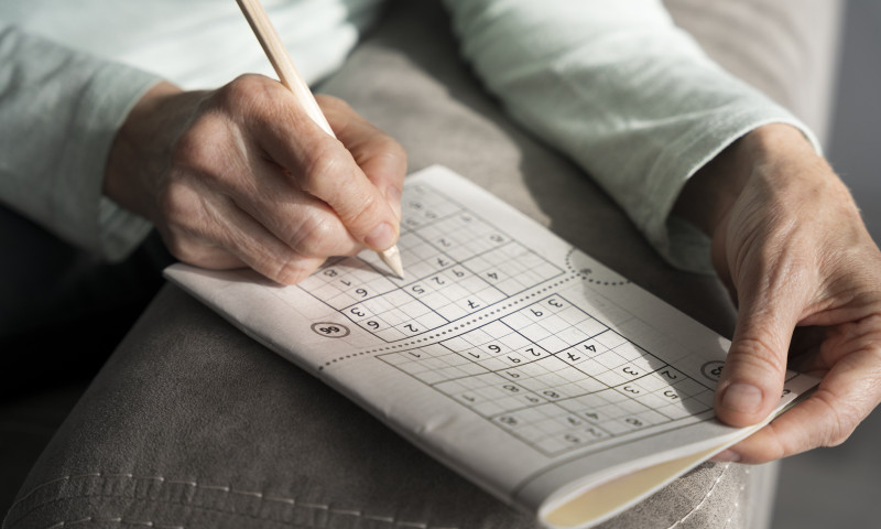 Elderly hands solving a sudoku puzzle with a pencil, staying mentally sharp after retirement