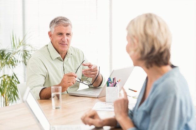 Older man gesturing during a retirement consultation, discussing financial goals with an advisor across a desk