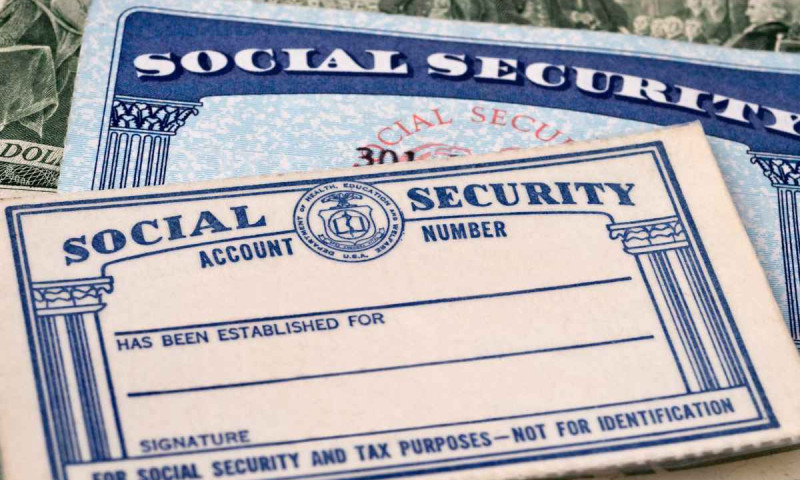 Two blank Social Security cards overlapping on U.S. currency, representing concerns about Social Security running out of funds