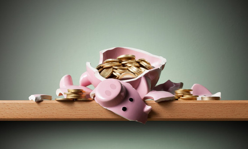 Broken pink piggy bank spilling gold coins, illustrating how to access retirement savings before 59 without triggering early withdrawal penalties