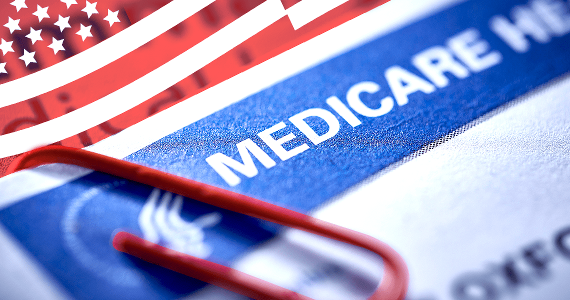 Close-up of a Medicare Health Insurance card with a red paperclip next to an American flag