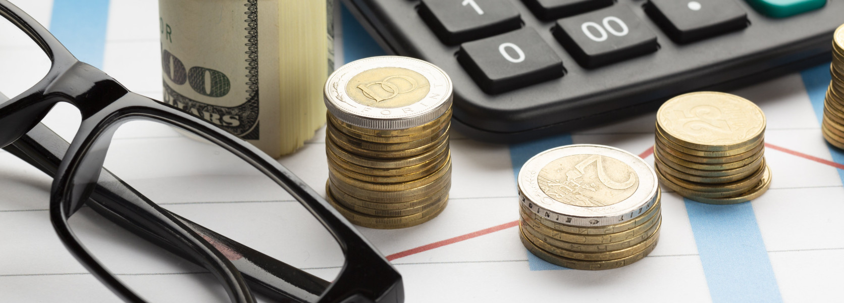 Stacked coins beside a calculator and rolled banknote, illustrating how investment fees quietly erode retirement savings