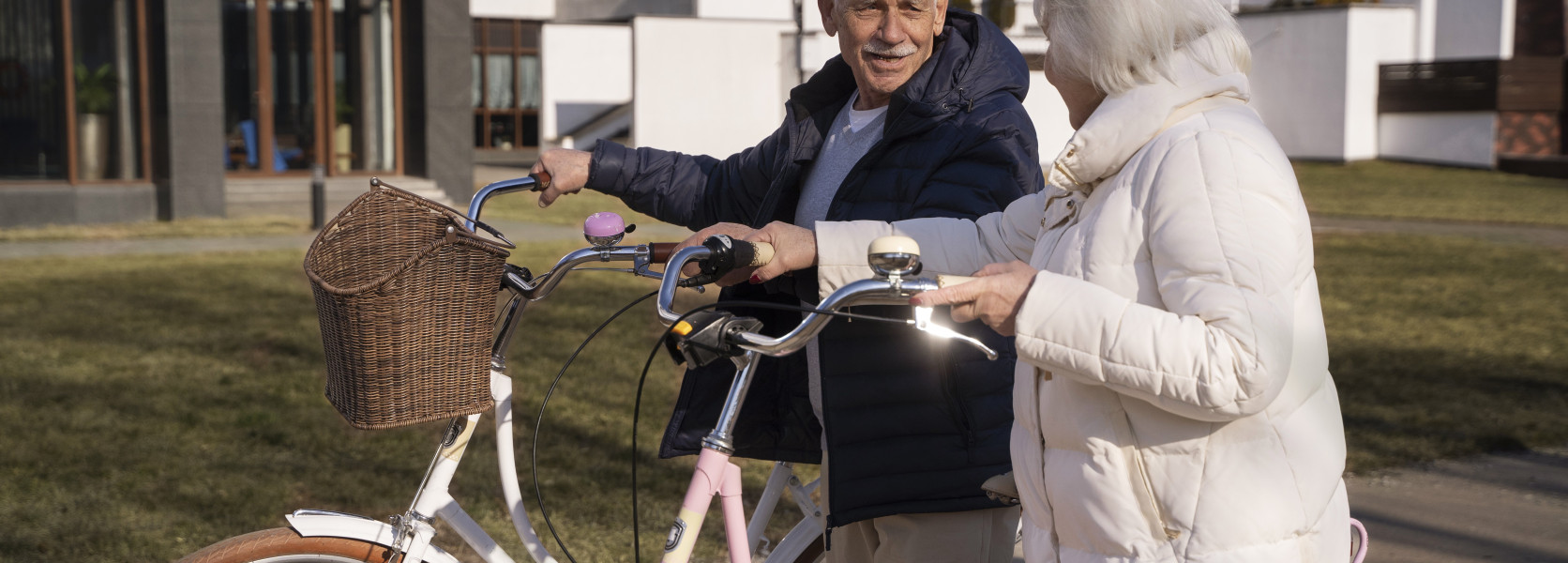 Senior couple with bicycles outside a modern building on a sunny day, finding the best small towns to retire in 2025