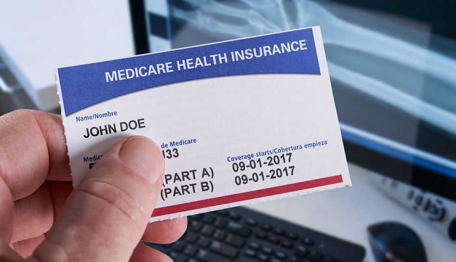 Hand holding a Medicare Health Insurance card showing Part A and Part B coverage start dates