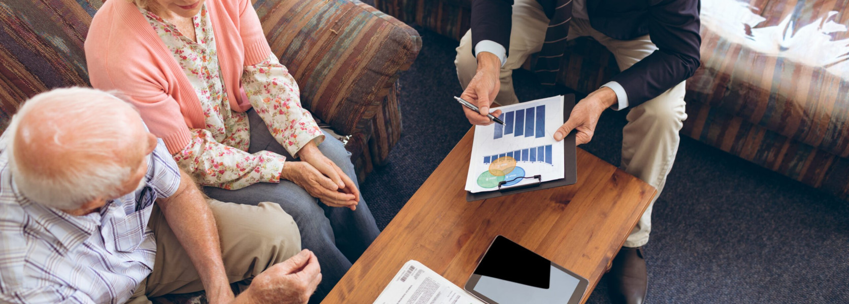 Financial advisor presenting a bar chart to a retired couple, explaining how to diversify a retirement portfolio