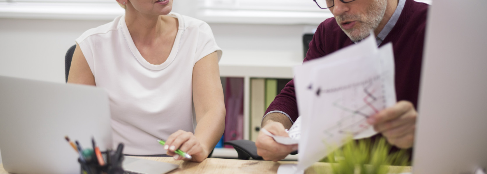 Two colleagues at an office desk reviewing printed charts, navigating what to do when an employer changes 401(k) providers