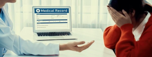 Doctor pointing to a medical record on a laptop screen while a patient sits across, representing fixing Social Security record errors