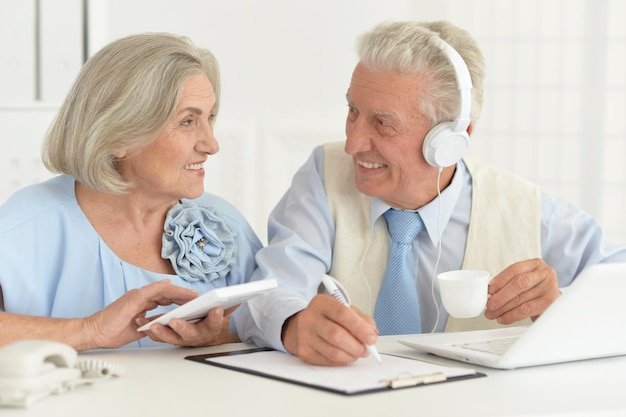 Older couple smiling and reviewing paperwork at a desk, evaluating health insurance options to bridge coverage in early retirement