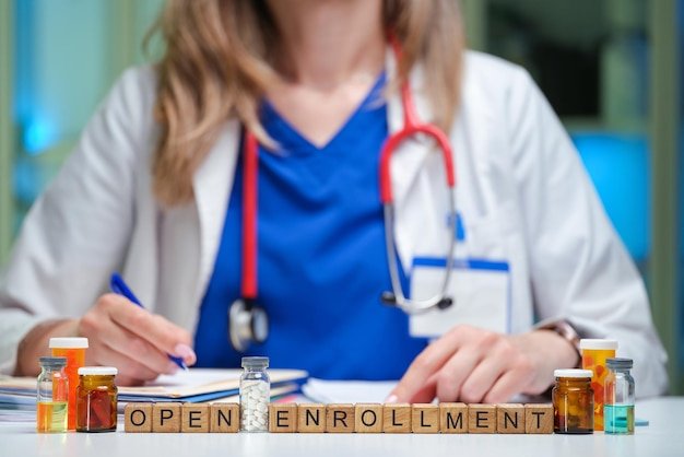 Doctor with stethoscope sits near blocks spelling Open Enrollment, illustrating Medicare Advantage open enrollment