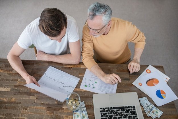 Two men analyzing financial charts and pie graphs, preparing a portfolio for retirement market downturns