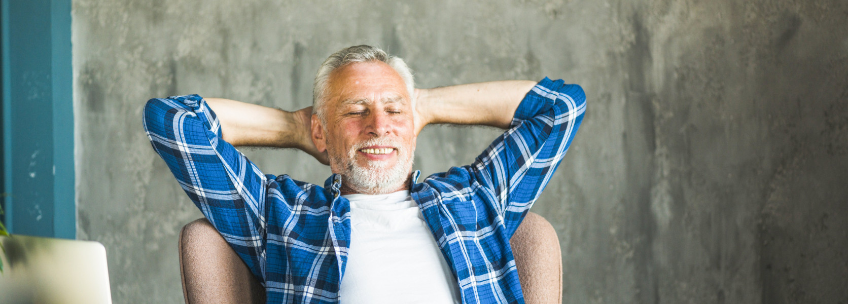 Relaxed older man leaning back at a desk with a laptop, enjoying the structured free time he created after leaving work early