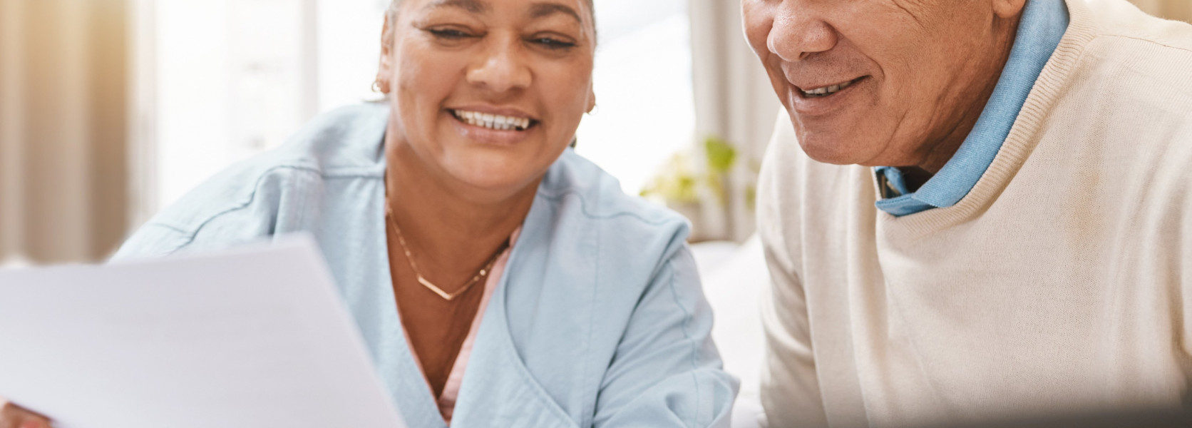 Smiling senior couple reviewing financial paperwork with a calculator, understanding required beginning dates for RMDs