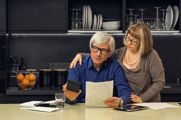 Senior couple reading a retirement document together in the kitchen, reflecting on lessons learned from retirees