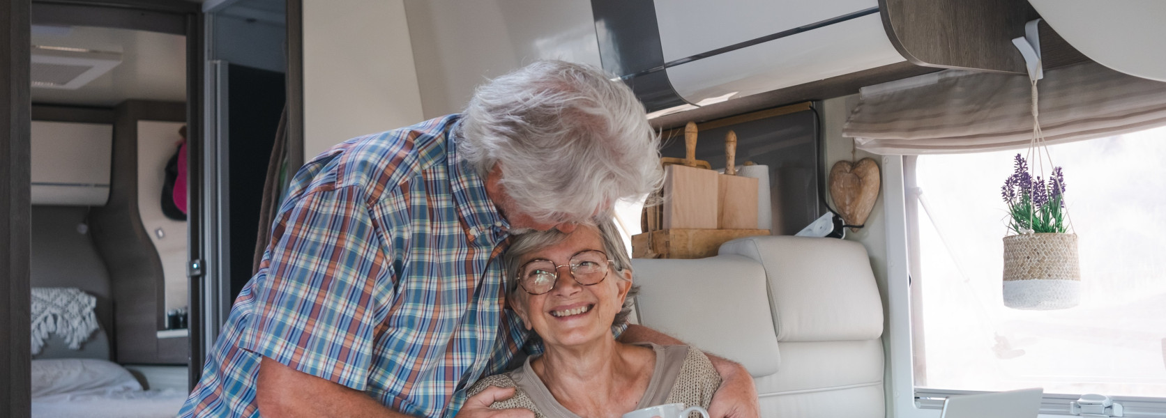 Senior couple laughing inside a modern RV camper van, considering whether RV life is right for them
