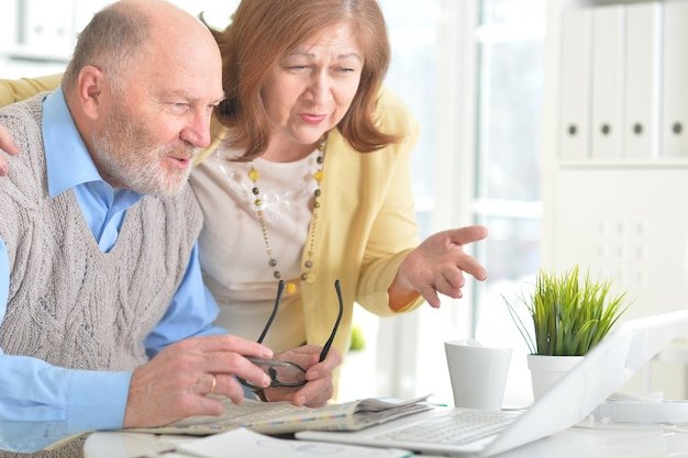 Senior couple reviewing documents on a laptop at home, planning what happens to a 401(k) after retirement