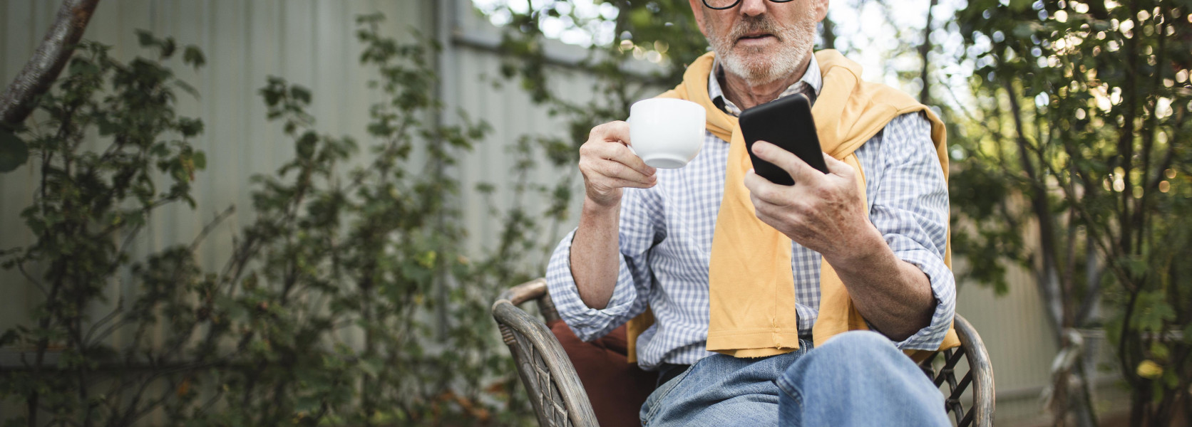 Middle-aged man relaxing in a garden chair with coffee and a phone, embracing the FIRE movement lifestyle